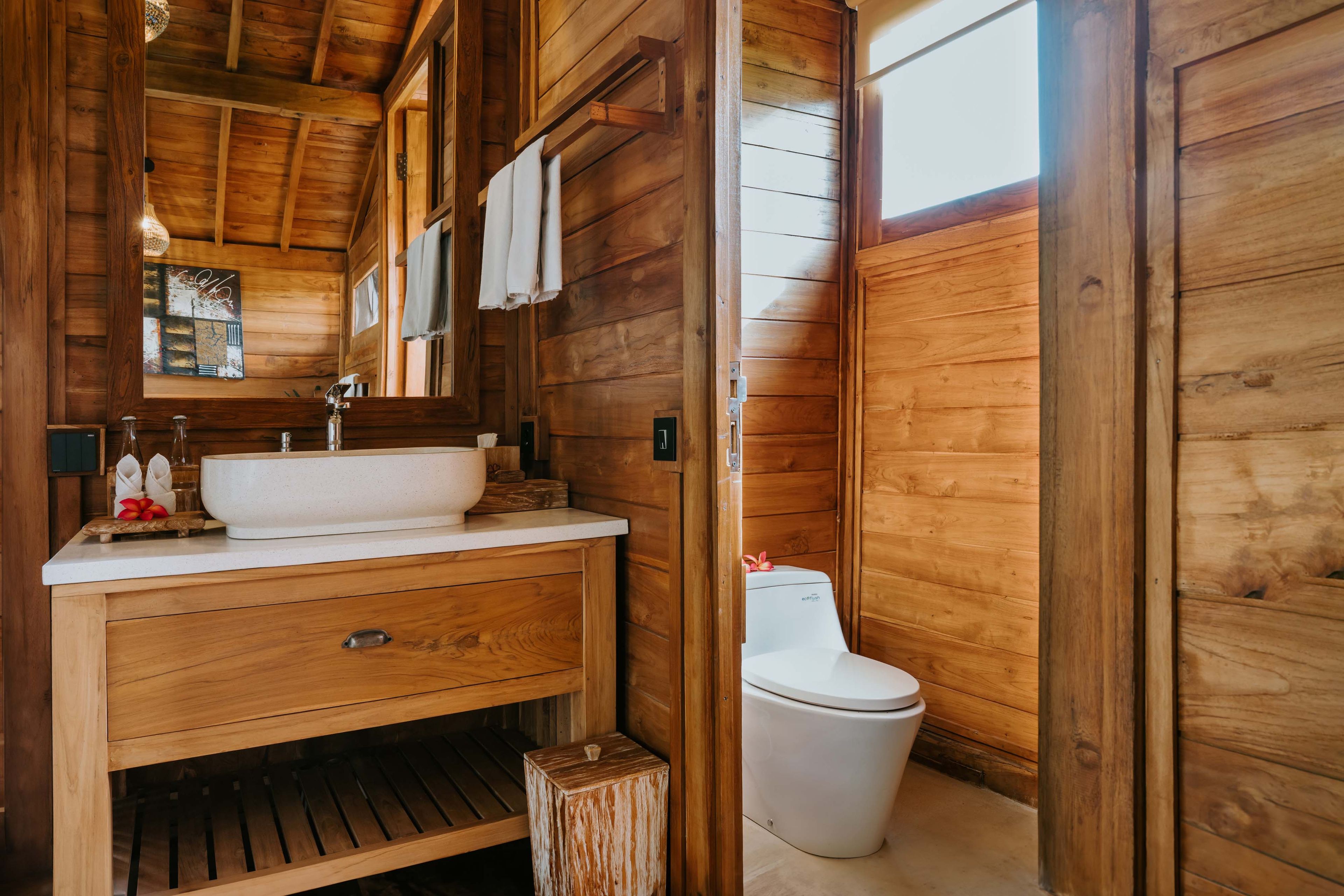 A wooden cabin bathroom with a wooden vanity, a sink, and a toilet.