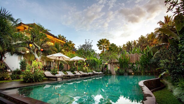 A pool area with lounge chairs and umbrellas, surrounded by lush tropical plants. - The Kalyana Ubud Resort (Ubud)