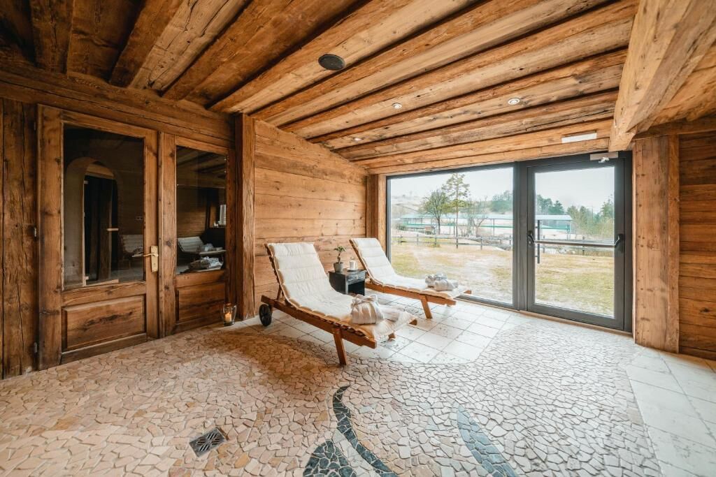 Un interior de madera con piso de mosaico, dos sillones de descanso y un ventanal con vistas al exterior.
