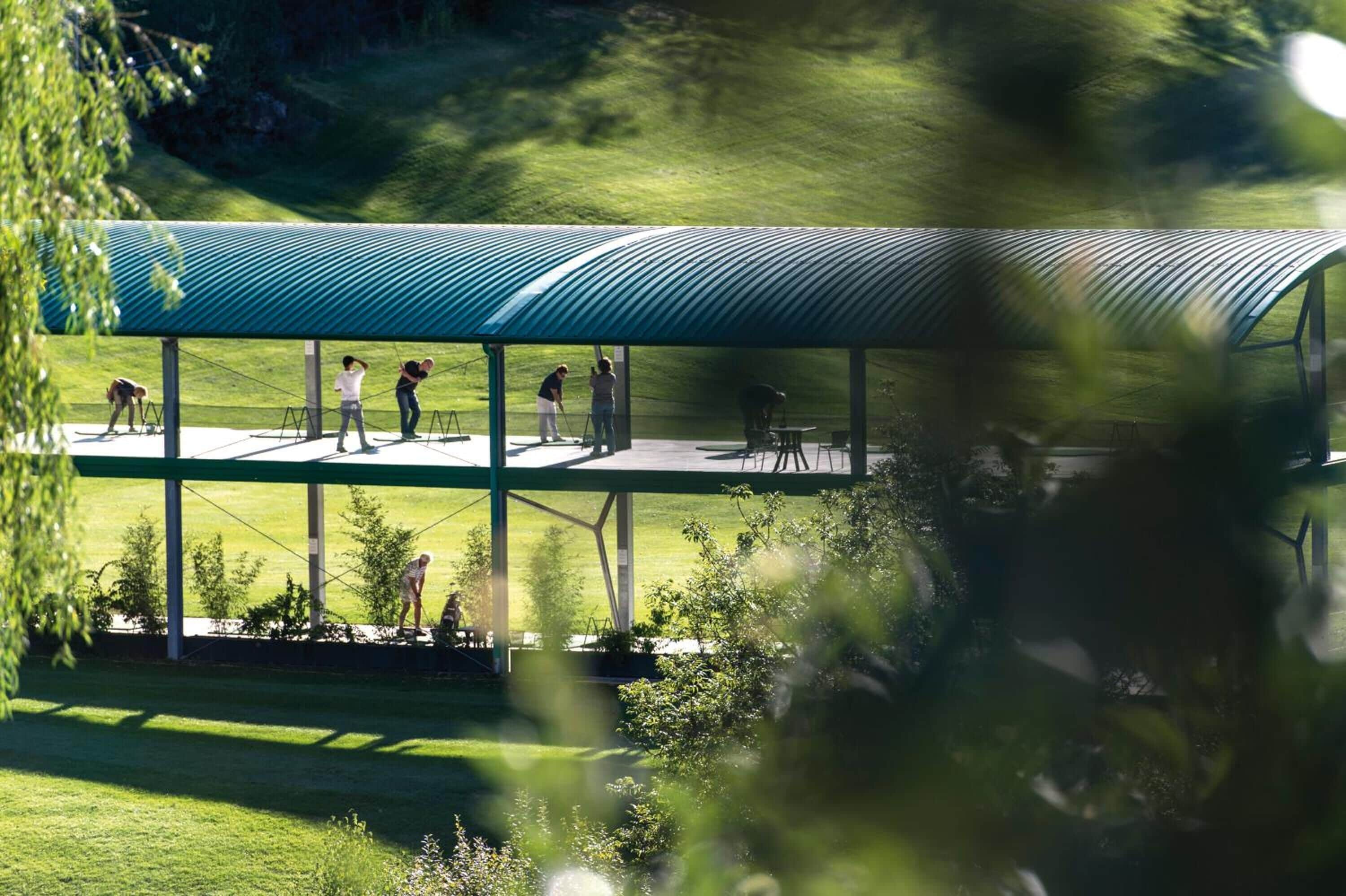 A covered outdoor area with a metal roof, surrounded by greenery.