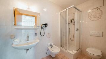 Une salle de bain équipée d’un lavabo, d’un bidet, de toilettes et d’une douche à parois de verre.