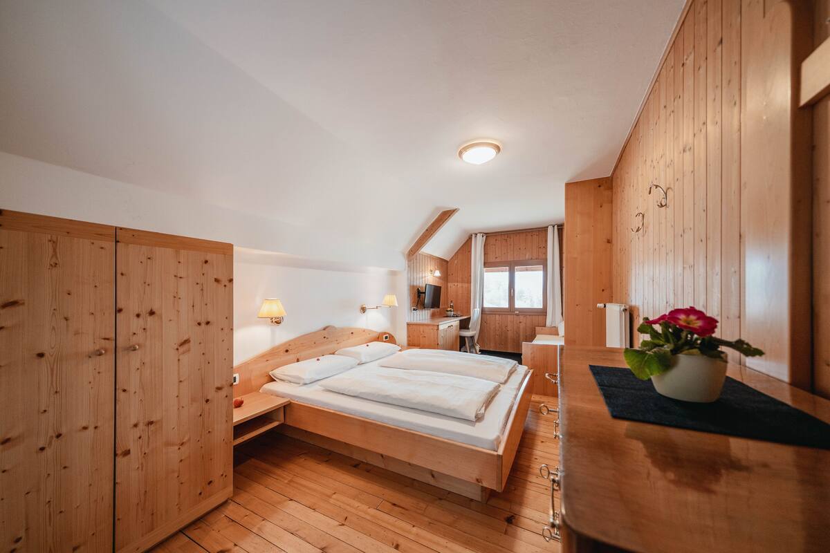 A wooden room with a bed, a desk, and a chair.