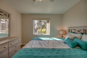 Cozy retreat with a large bed, dresser, and window with blinds.