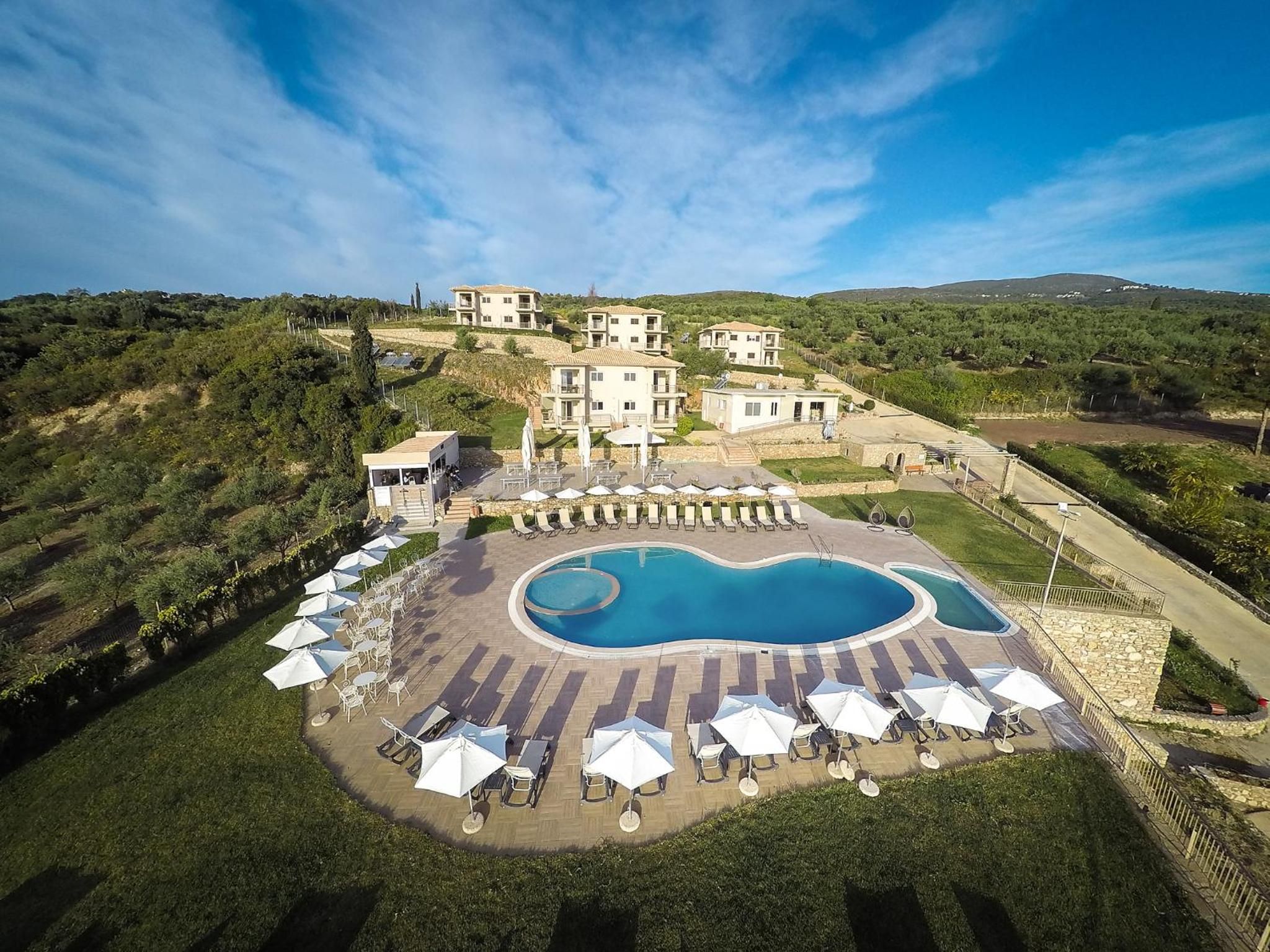 A resort with a swimming pool, outdoor seating, and hillside villas.
