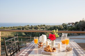 A breakfast setup on a balcony with a view of the sea and greenery. - Baywatch Hotel (Messini)