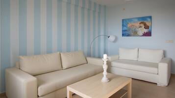A living room with two beige sofas, a wooden coffee table, a floor lamp, and a painting on the wall.