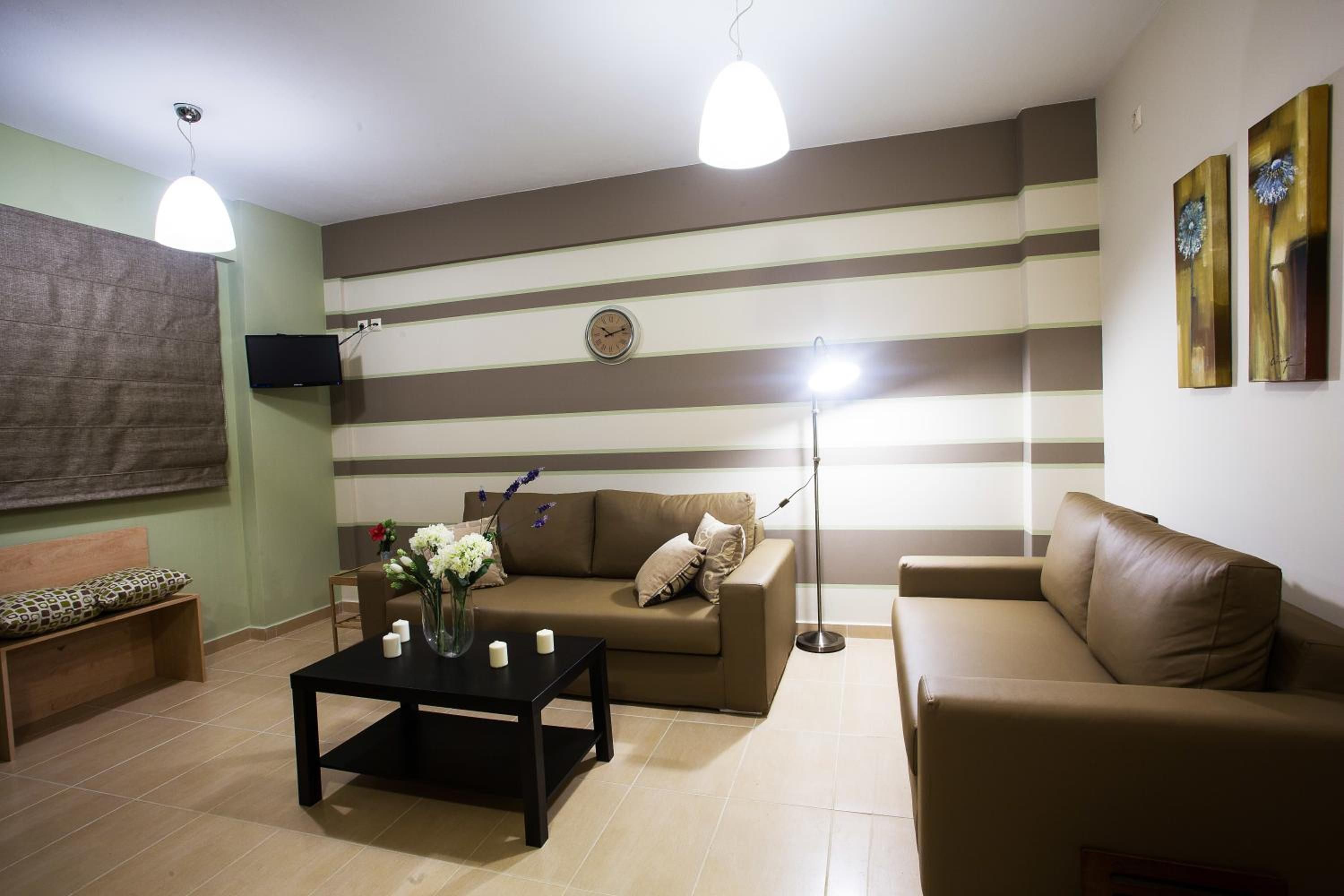 Una sala de estar con paredes a rayas, un sofá, una mesa de centro y un televisor montado en la pared.