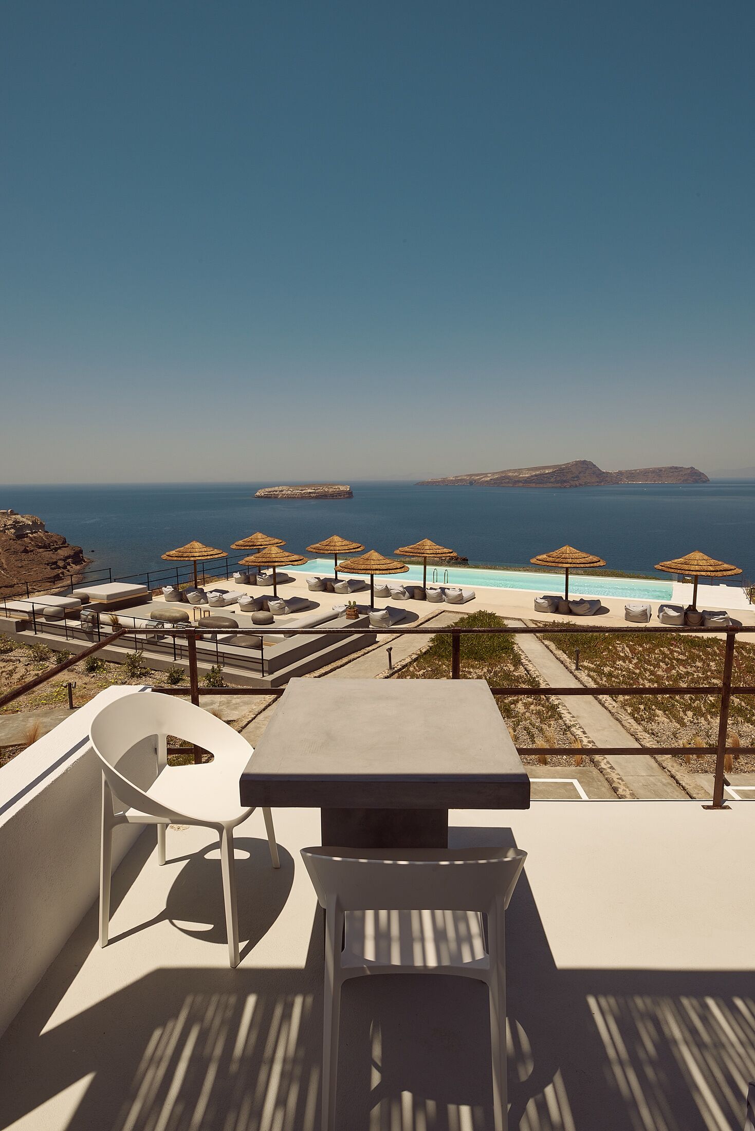 A rooftop terrace with a pool, lounge chairs, and umbrellas overlooking the sea.