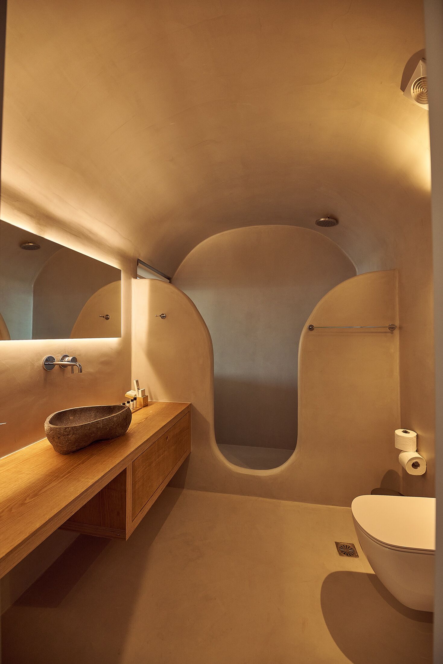 Un baño moderno con un lavabo de piedra, tocador de madera y un inodoro blanco.