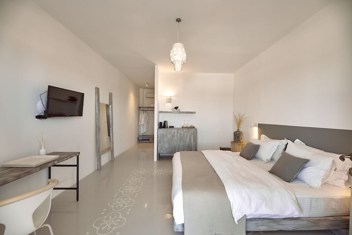 A modern bedroom with a bed, bedside table, and a TV mounted on the wall.
