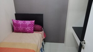 Une petite chambre à coucher, bien rangée, avec un lit, des oreillers et une table de chevet.