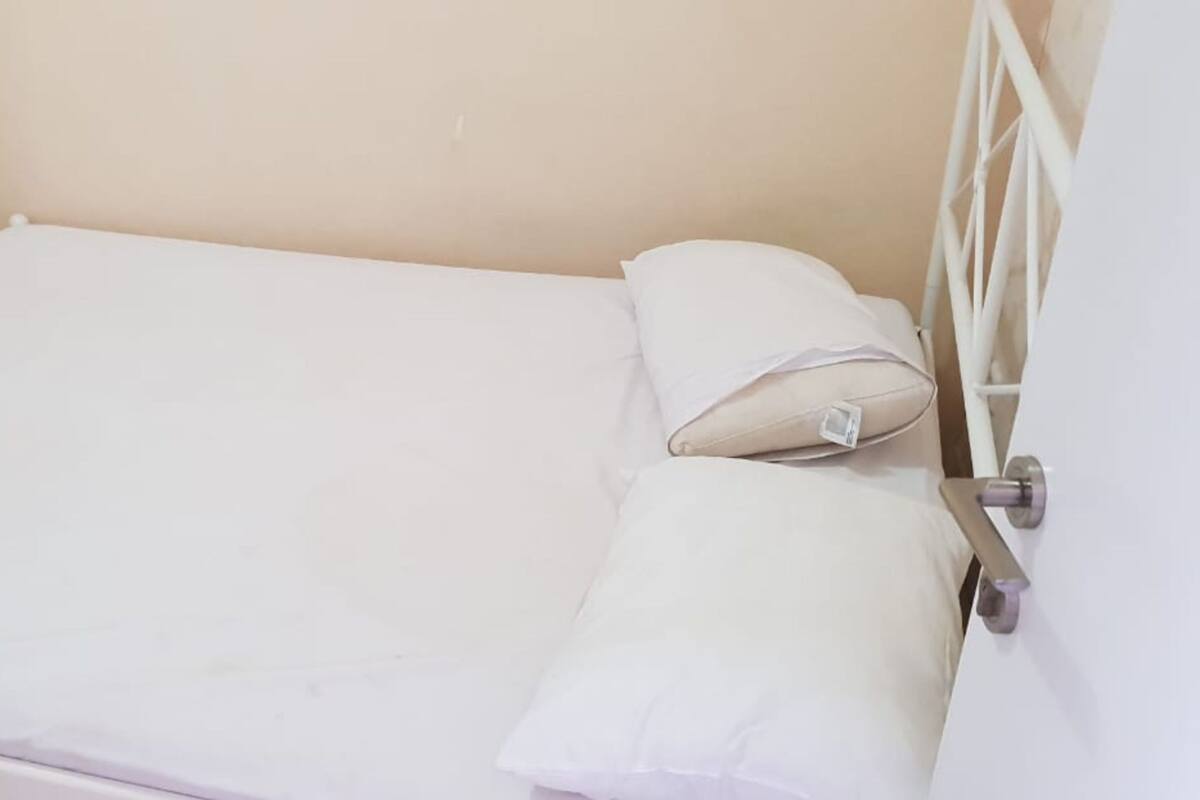 Ein Einzelbett mit weißer Bettwäsche und einem Metallgestell.