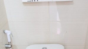 Une salle de bain avec des toilettes blanches, un bidet et un porte-rouleau de papier toilette.
