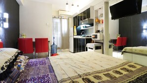 Una habitación de hotel con una cama, un escritorio, un televisor y una silla roja.