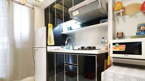 Una cocina compacta con refrigerador, microondas y estufa.