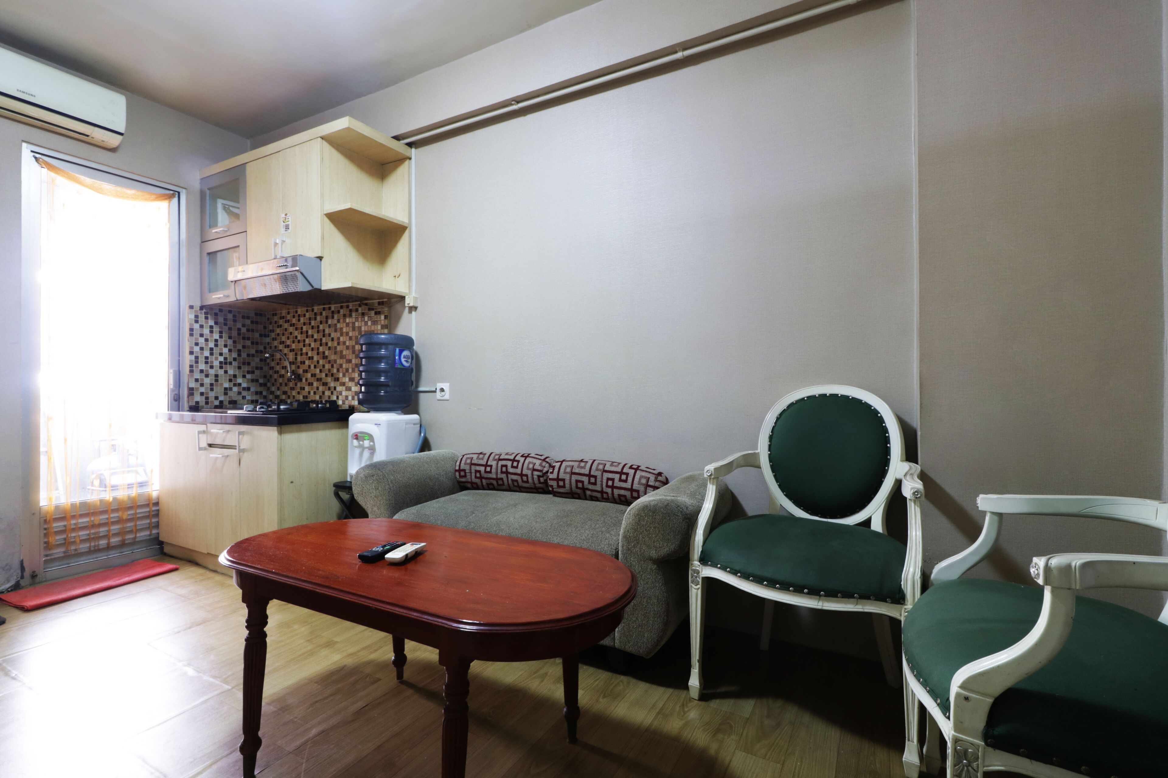 A compact living space with a kitchenette, a sofa, two chairs, and a small table.