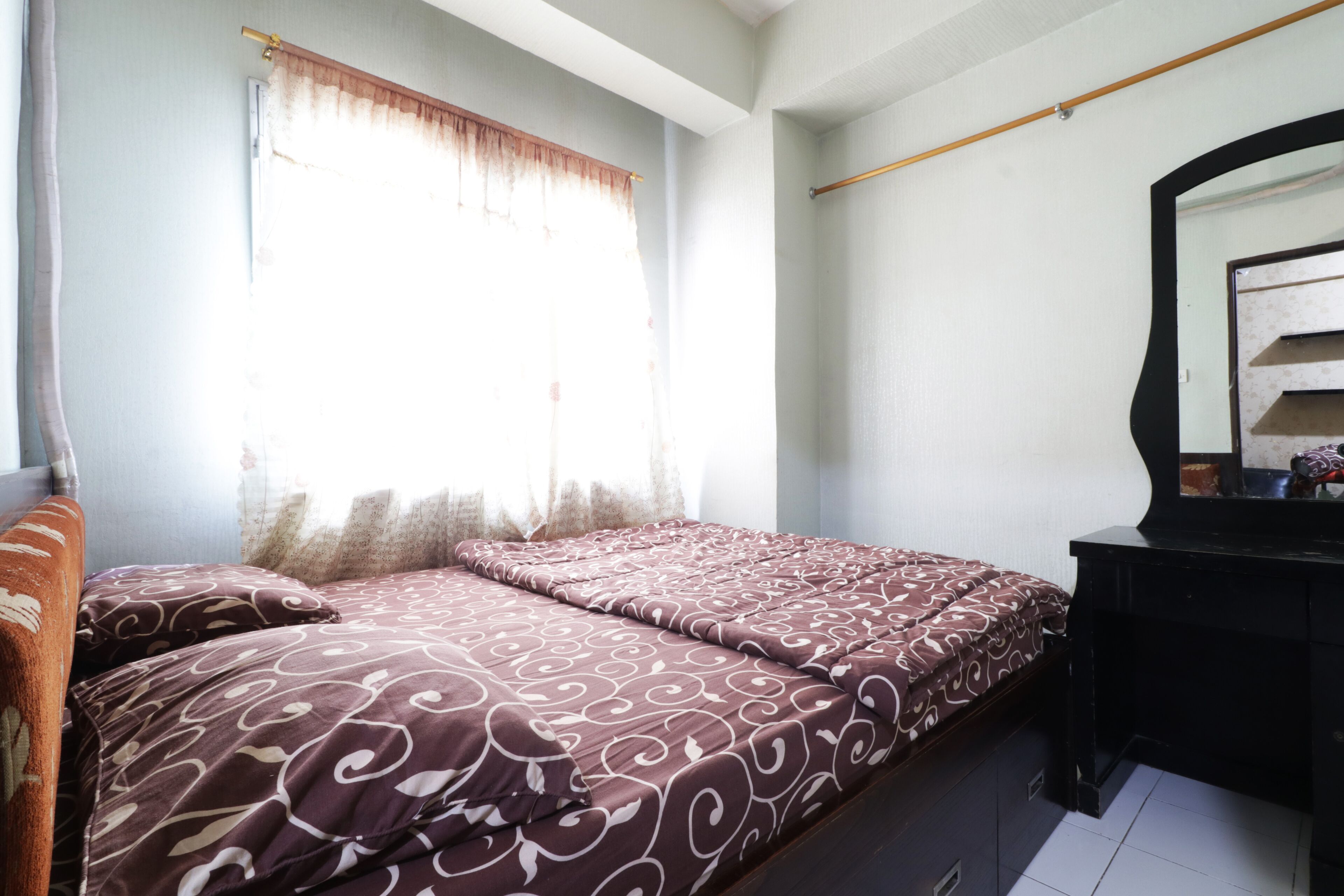 Une chambre à coucher avec un lit, une commode et un miroir.