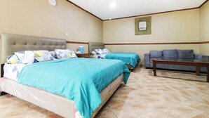 A hotel room with two beds, a sofa, a wooden table, and a clock on the wall. - Hotel Alamanda (Jakarta)
