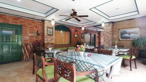 A dining area with a large table, chairs, and a ceiling fan. - Hotel Alamanda (Jakarta)
