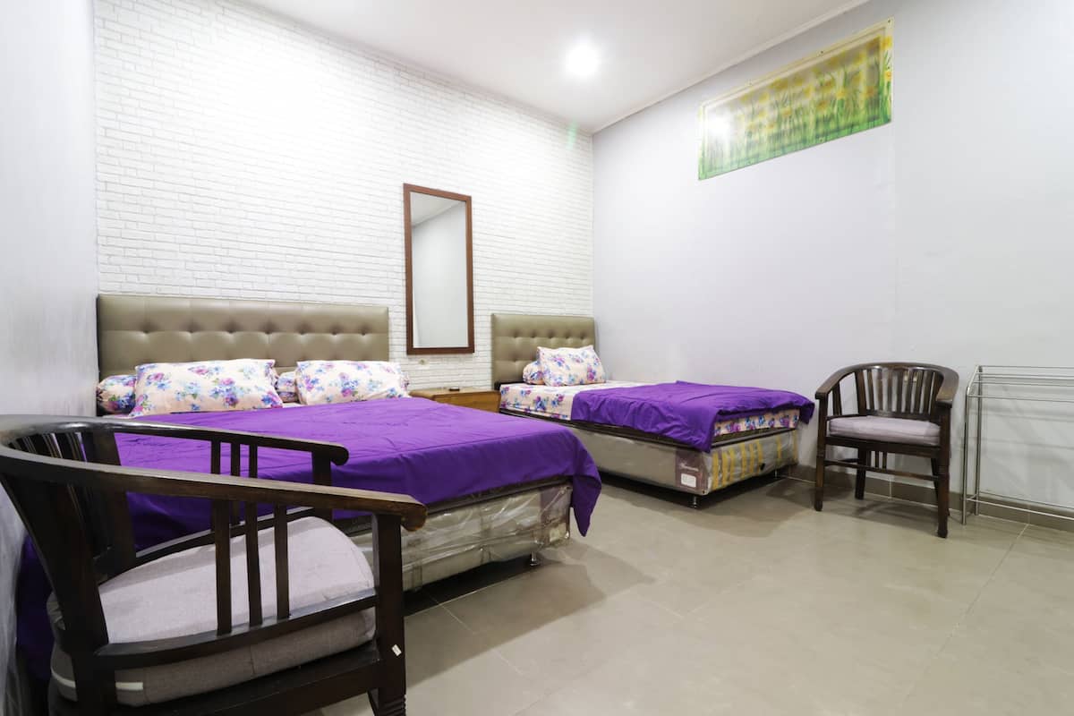 A room with two beds, a chair, a mirror, and a wall with a green and yellow pattern.