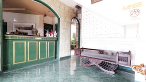 A reception area with a green counter, a bench, and a wall with a no-smoking sign. - Hotel Alamanda (Jakarta)