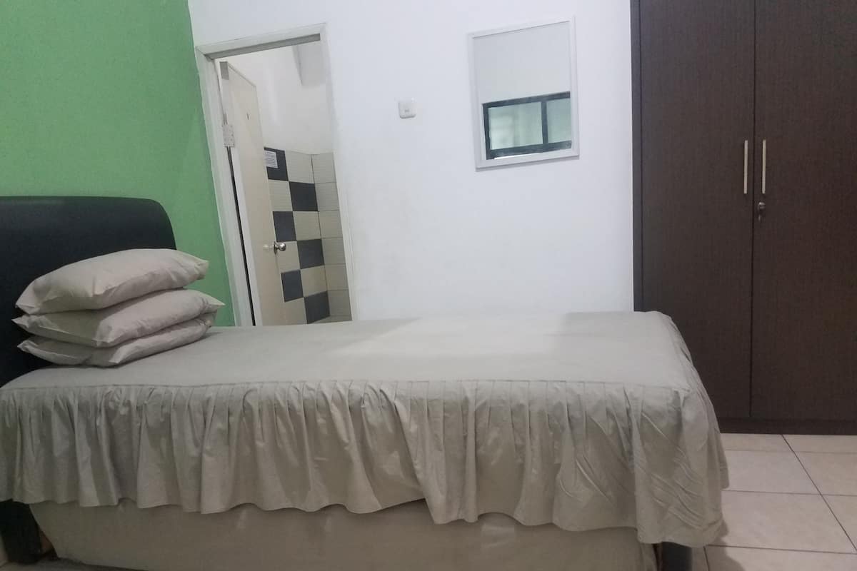 Una camera da letto con un letto, un armadio, una piccola finestra e una porta che dà su un'altra stanza.