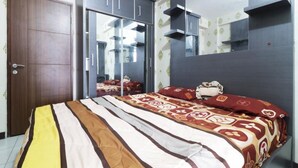 A bedroom with a bed, a wardrobe, a mirror, and built-in shelves. - Jo Rooms - Apartemen Betos (Bekasi)