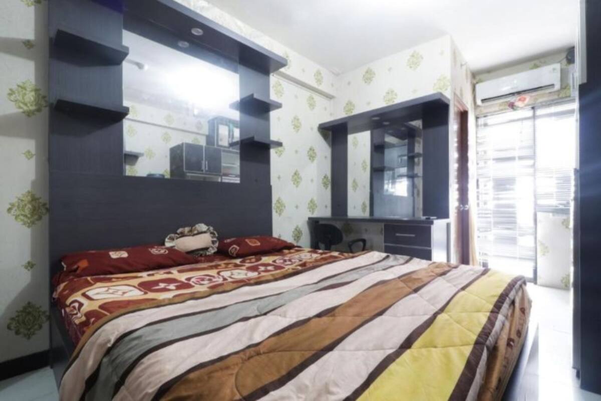 Une chambre à coucher avec un lit, une commode, un miroir et une fenêtre.