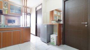 A kitchen with wooden cabinets, a refrigerator, and a microwave. - Jo Rooms - Apartemen Betos (Bekasi)