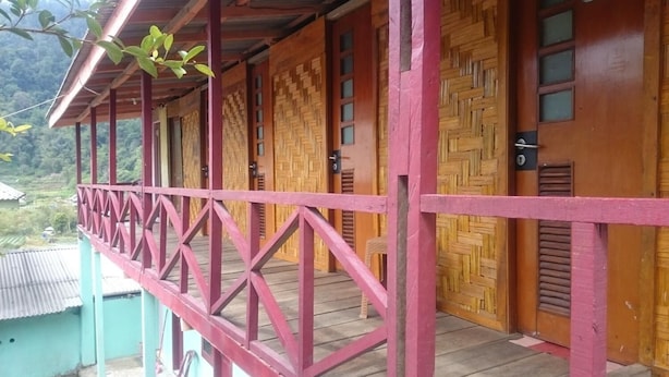 A wooden building with a balcony and doors. - Penginapan Biringta (Berastagi)