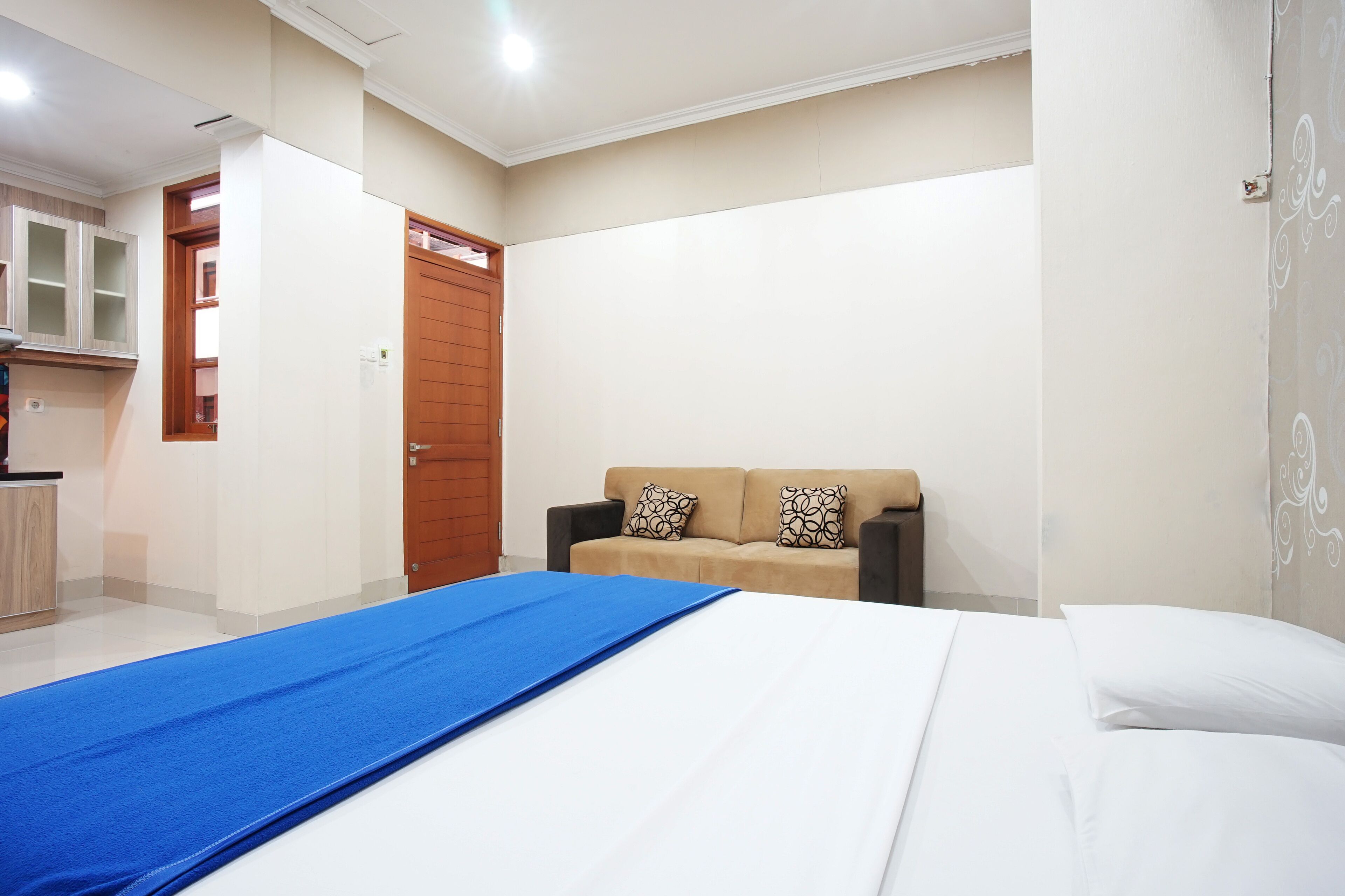 Una habitación de hotel con una cama, un sofá, un armario de madera y una puerta.