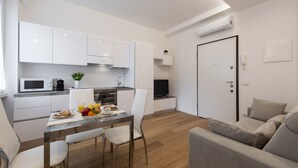Eine moderne Küche mit weißen Schränken, einer Mikrowelle und einem Essbereich mit Tisch und Stühlen.