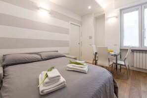 Habitación de hotel moderna con una cama grande, un escritorio con silla y una ventana con vistas.