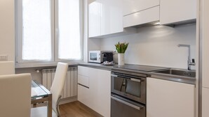 Eine moderne Küche mit weißen Schränken, Edelstahlgeräten und einem Fenster, das für natürliches Licht sorgt.