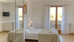 Habitación de hotel con cama, mesita de noche con lámpara, espejo y vistas al exterior.