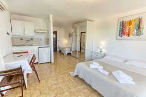 A hotel room with a bed, a desk, a chair, a small kitchenette, and a bathroom with a mirror. - Motel a Puntella (L'Île-Rousse)