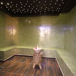 Relax in a serene space with a cozy seating area and a warm candlelit table.