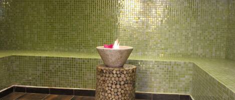 A tiled room with a small stool holding a candle.