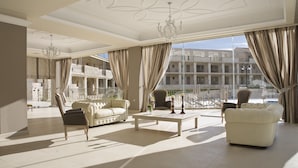 A spacious living room with a large window, a chandelier, and a balcony with outdoor furniture. - The Magnolia Resort - Adults Only (Kefalonia)