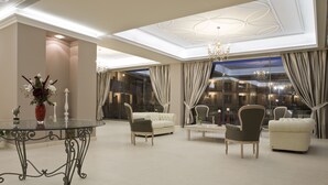 A spacious, elegantly furnished living area with a glass table, comfortable seating, and a chandelier. - The Magnolia Resort - Adults Only (Kefalonia)
