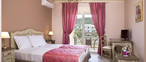 A bedroom with a bed, bedside tables, a TV, and a balcony with chairs.