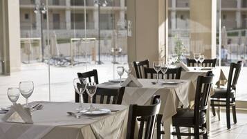 A dining area with tables set for two, chairs, and wine glasses.