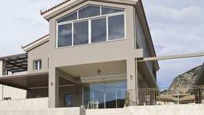 A modern two-story house with a large balcony, a stone staircase, and a view of the beach. - The Magnolia Resort - Adults Only (Kefalonia)
