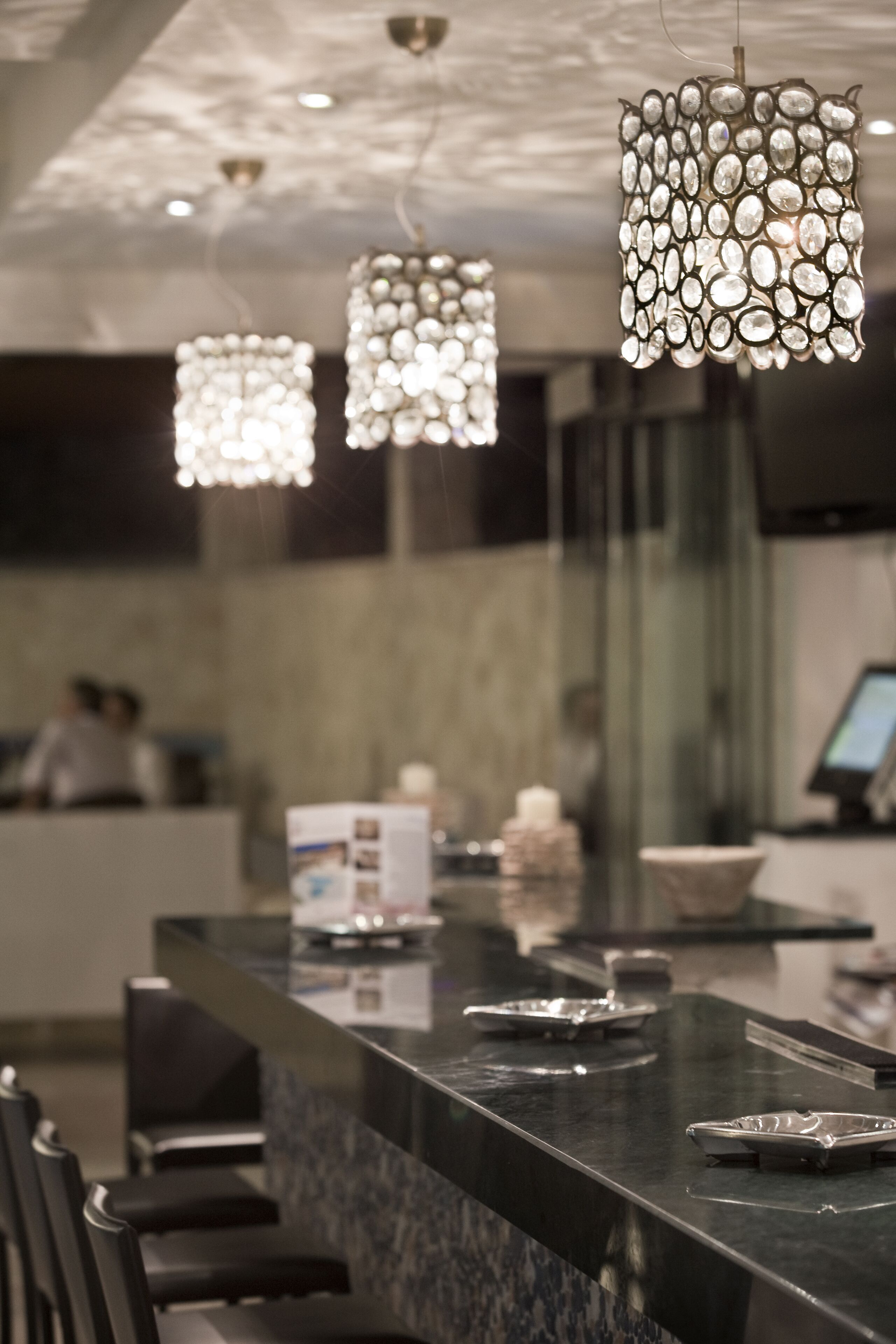 A reception area with a marble counter, black chairs, and decorative hanging lights.