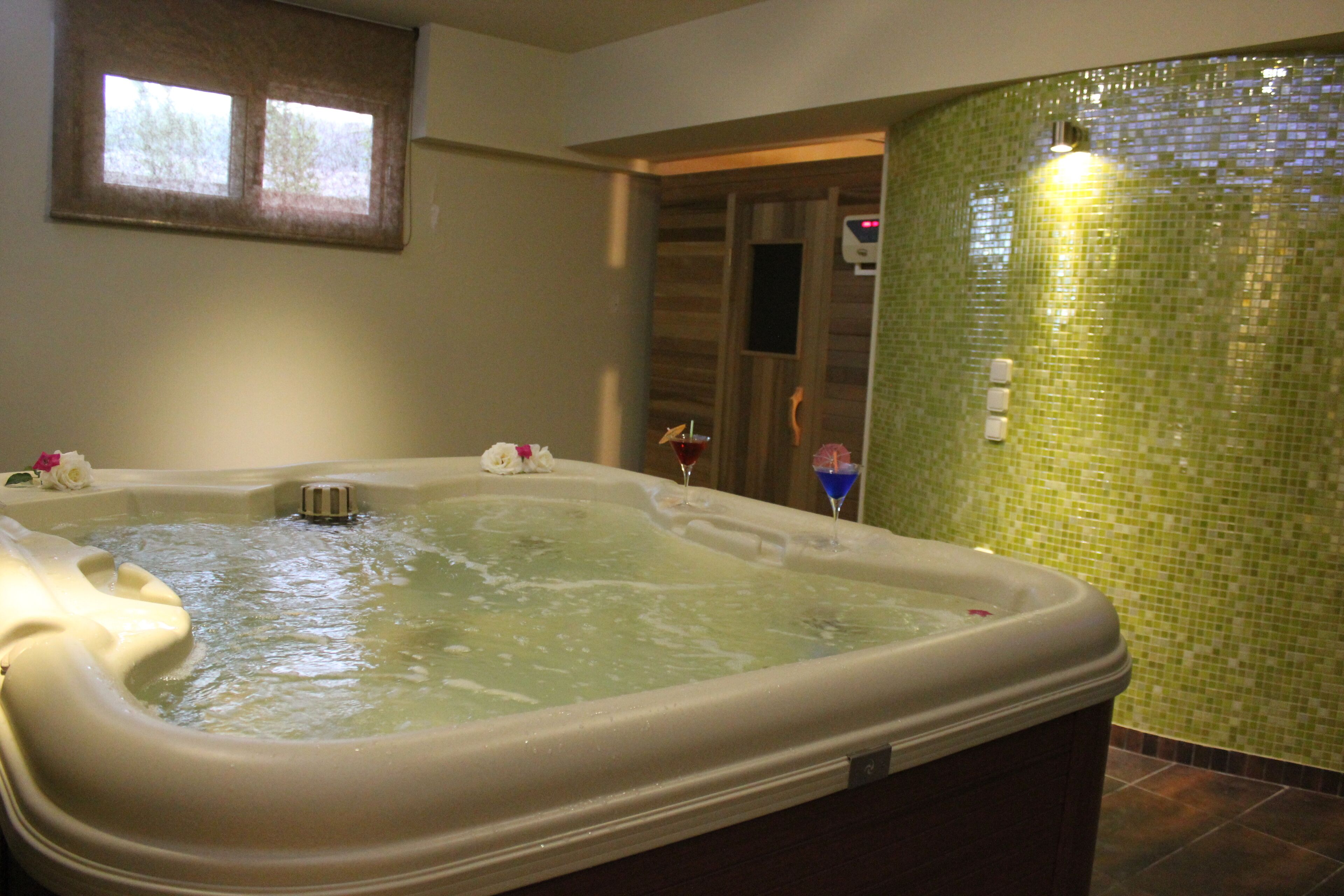 Un jacuzzi con agua, una ventana y una pared de mosaicos verdes.