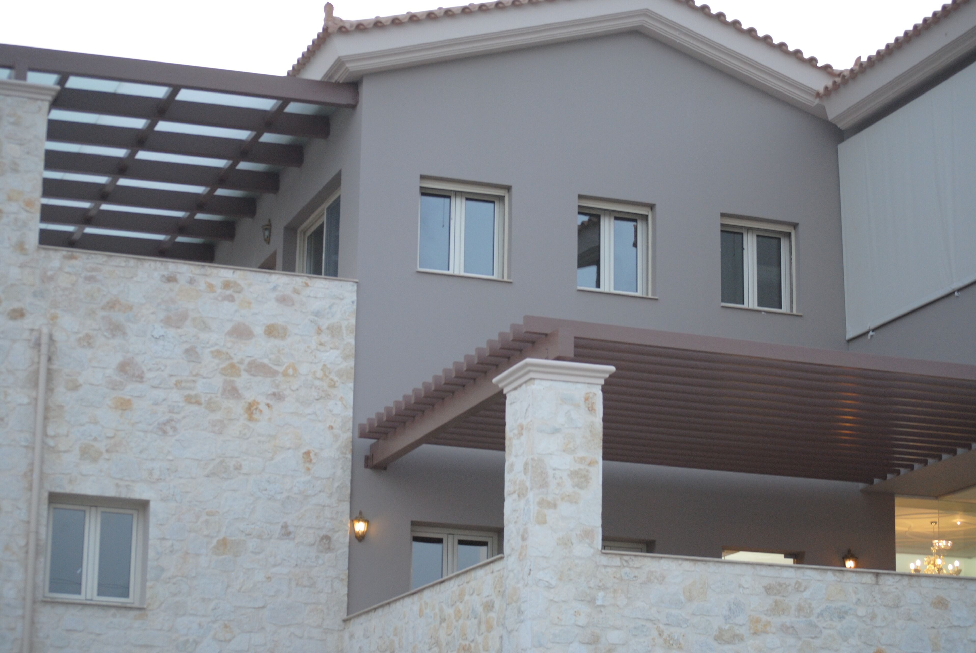 A multi-story building with stone facade, multiple windows, and a covered outdoor area.