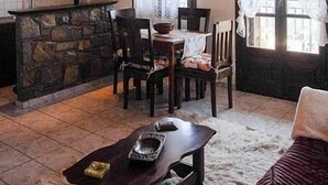 A rustic interior with a stone fireplace, wooden dining table, and chairs. - Traditional Charming Stone Chalet (Distomo-Arachova-Antikyra)