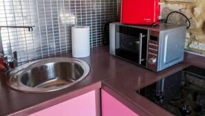 A kitchen with a stainless steel sink, a microwave, and a red toaster on the countertop. - Antique Luxury Groundfloor Suite (Kalavrita)