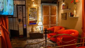 A cozy room with a red sofa, a wooden cabinet, a mirror, and a television. - Antique Luxury Groundfloor Suite (Kalavrita)