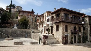 A stone building with a balcony, steps leading to the entrance, and a clear sky. - Antique Luxury Suite 75sq.m. (Kalavrita)